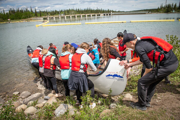 Participants in the WILD program working together to launch a big canoe.